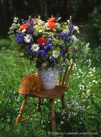 Blandade blommor i vas på stol